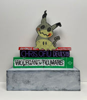 (Jonathan Edelhuber) "Still Life With Pokemon Sculpture on Art Books"